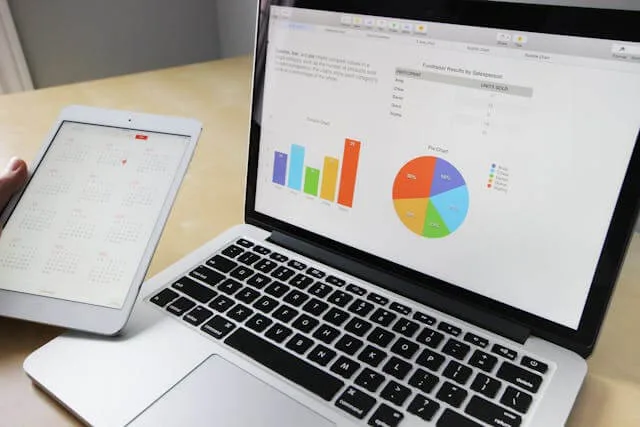 A laptop showing bar and pie charts beside a tablet calendar