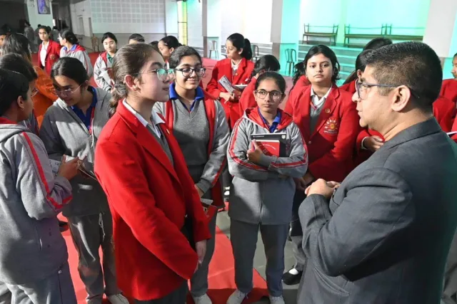Students in school uniform gathered around a speaker, still talking after the session has finished.