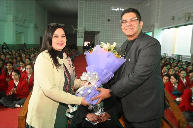 A bouquet being presented on stage at the start of the session, with the school hall full of students behind.