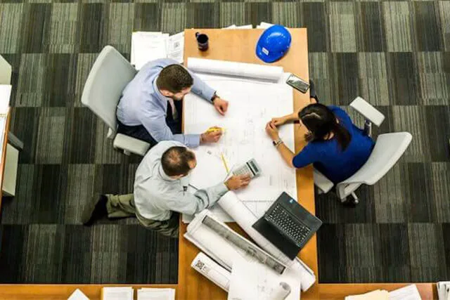 Three engineers reviewing building plans around a table