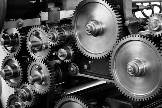 Interlocking steel gears and shafts inside a machine, in black and white